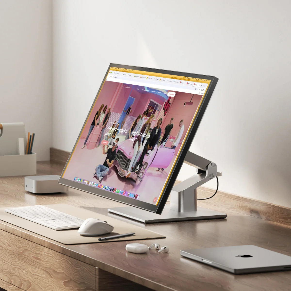 Modern desk setup with a computer monitor, keyboard, mouse, and laptop on a wooden surface.